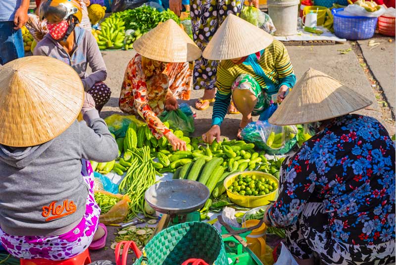Local women buying and selling vegetables at a Mekong Delta market, Vietnam with GeoEx