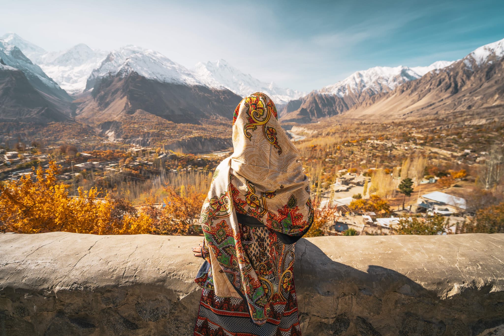 person with a patterned headscarf facing away from the camera and facing a vista