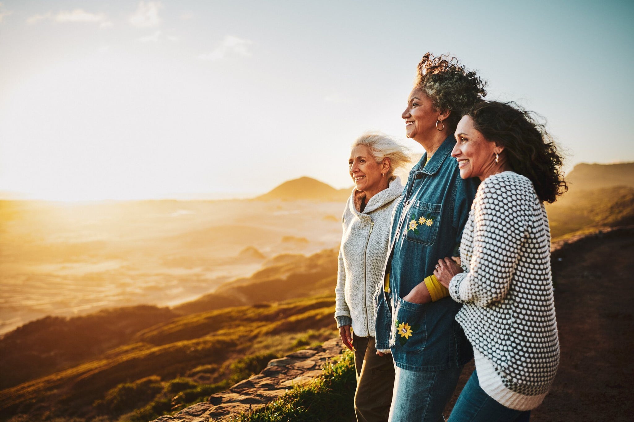 A picture of three women standing close to each other on a hill