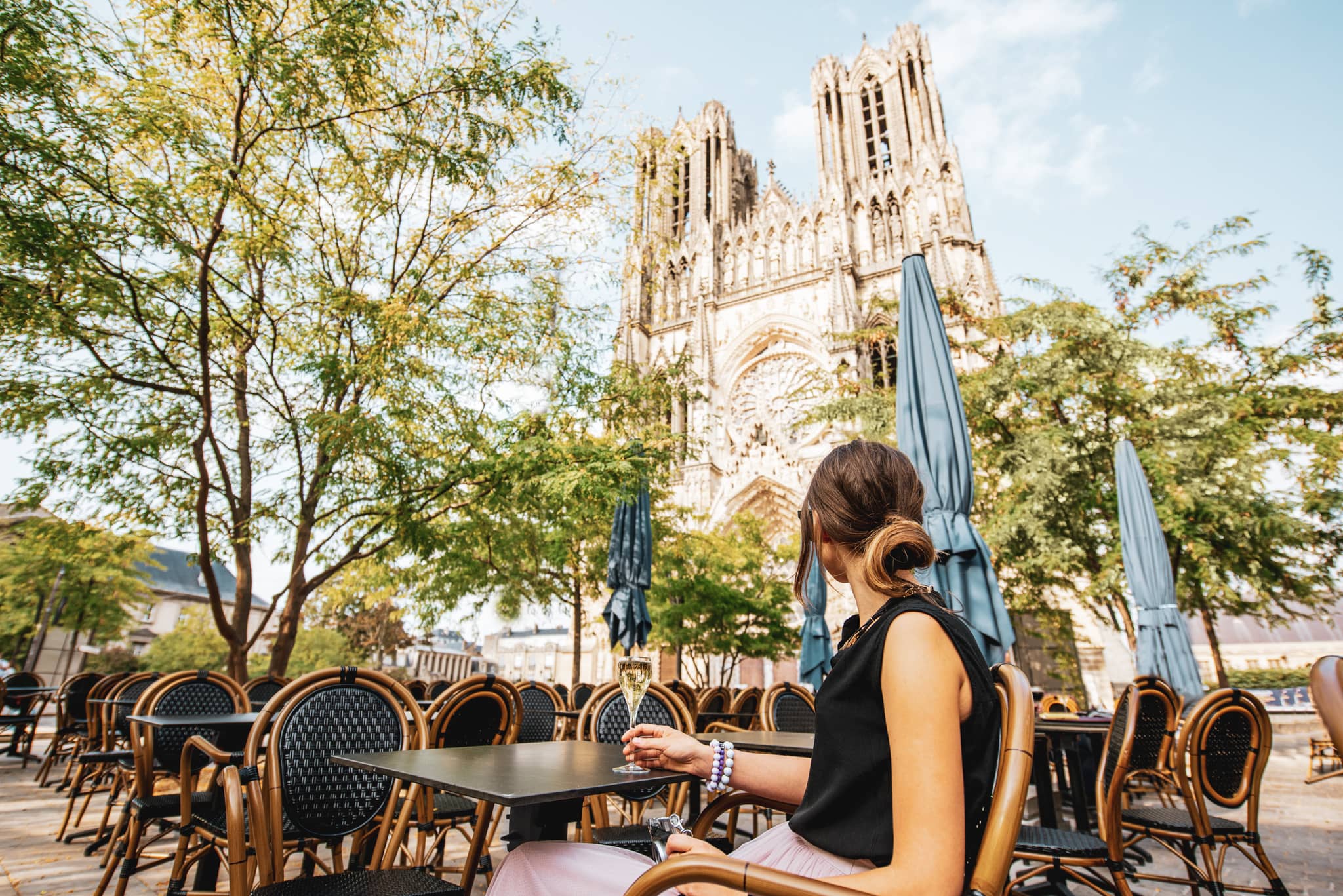 Woman sipping champagne in front of the cathedral in Reims, France