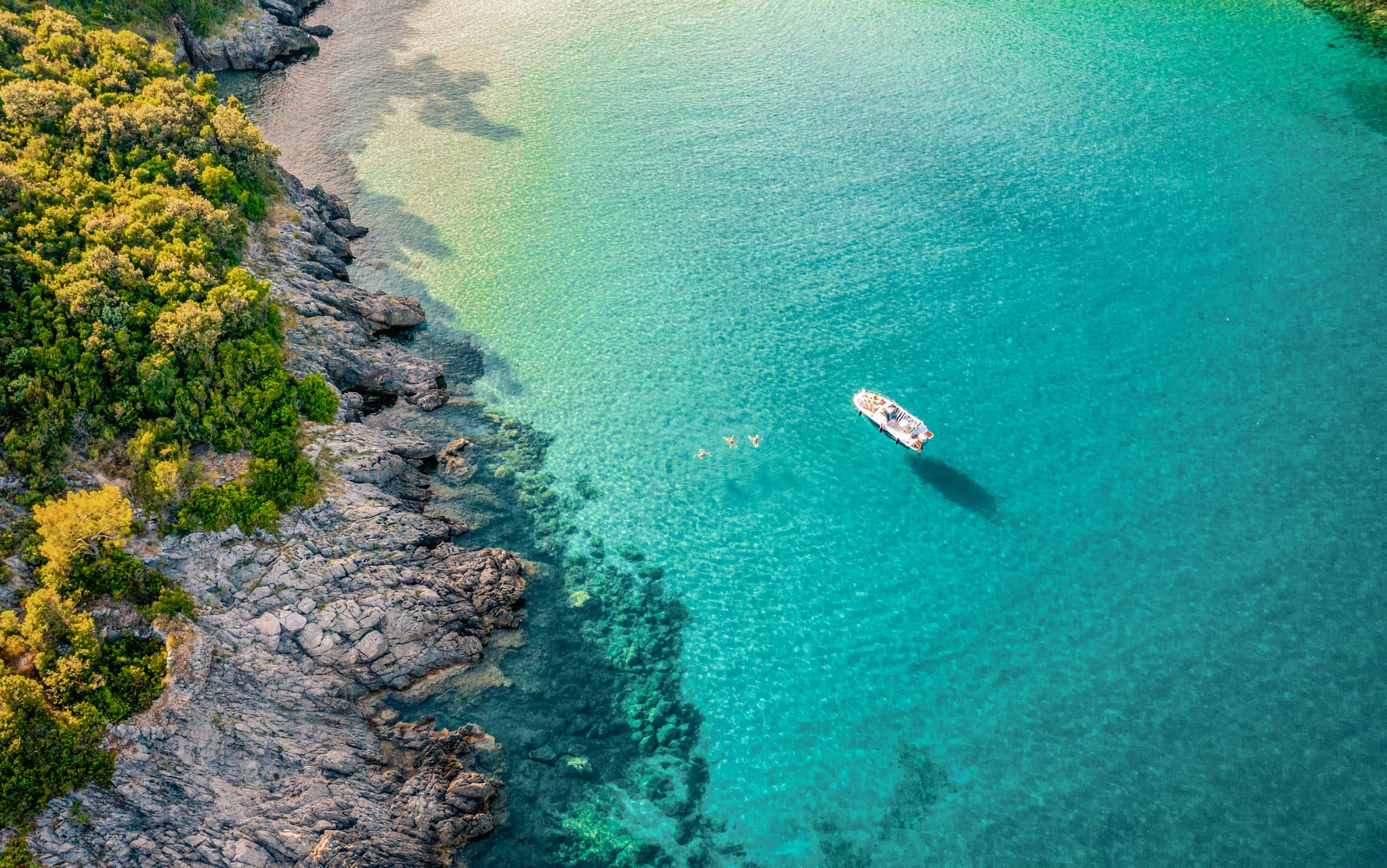 Aerial view of a boat in the Adriatic Sea with people swimming the the water, Montenegro
