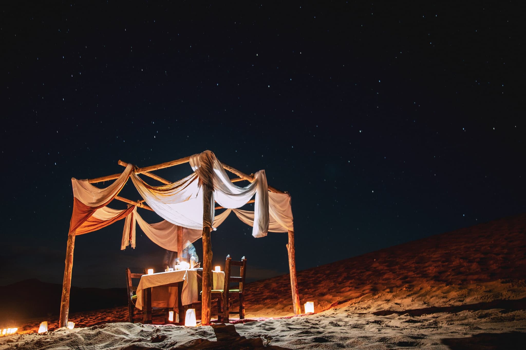 Luxury desert dining setup under the stars, representing exclusive experiences from premier access travel services.