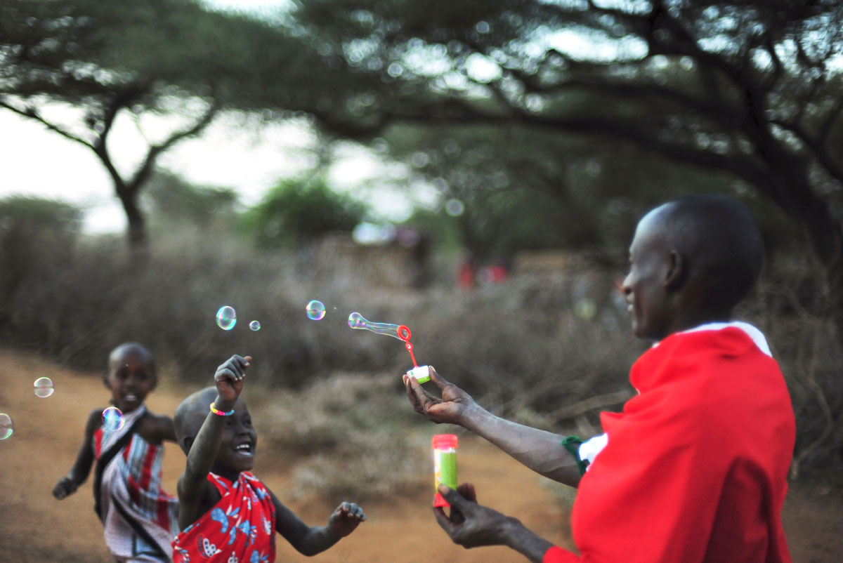 A Maasai man blowing bubbles for children in Africa, with GeoEx