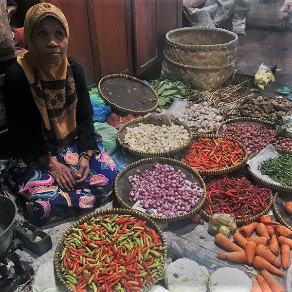 A seller surrounded by vegetables at a Yogyakarta, Indonesia market