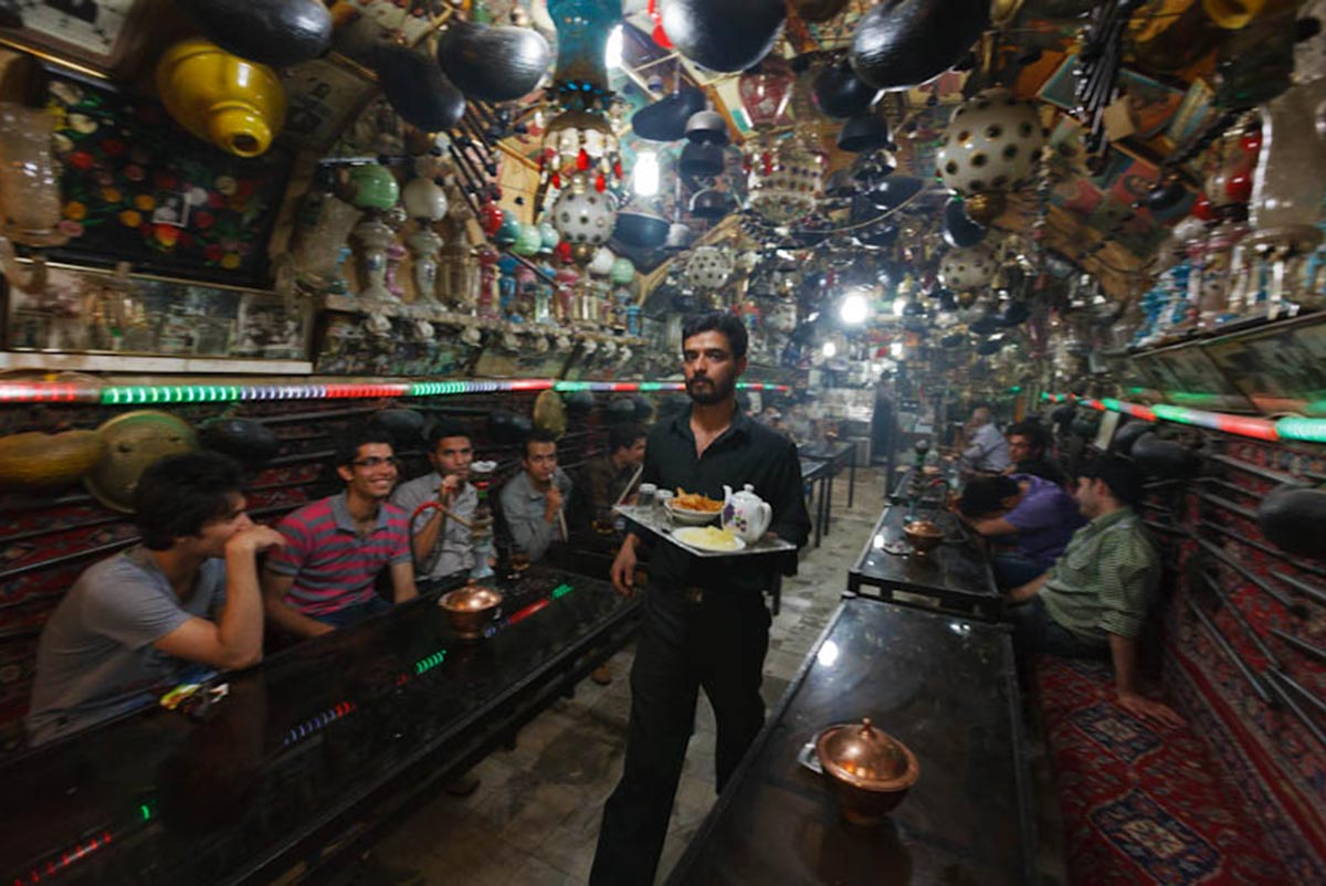 A waiter walks through a busy teahouse in Esfahan's bazaar, Iran.