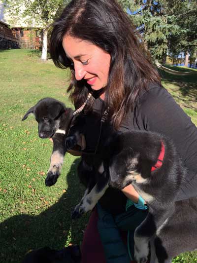 Jennine Cohen holding huskie puppies in Alaska with GeoEx.