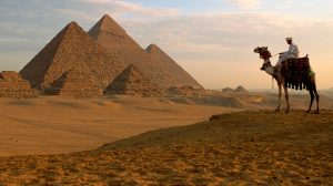 A man on a camel looks at the Giza Pyramids, Egypt