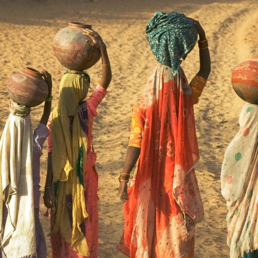 Girls wearing saris and holding water jugs in Rajasthan, India with GeoEx