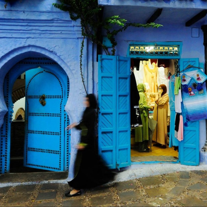 A woman walking down a street in the Chefchaouen medina, Morocco