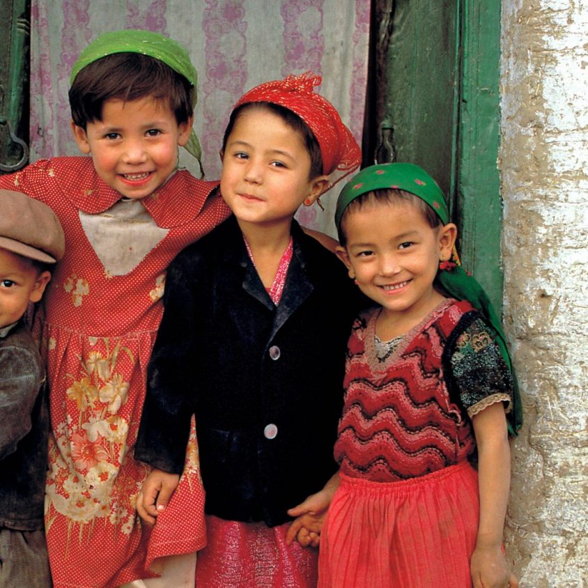 Friendly children smile from their doorway in Kashgar, China, Silk Road