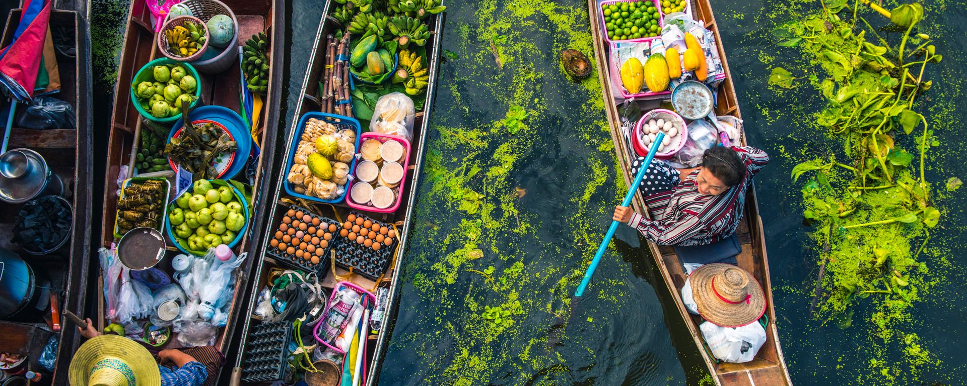 Female vendor sells food from a longtail boat at a floating market in Bangkok, Thailand