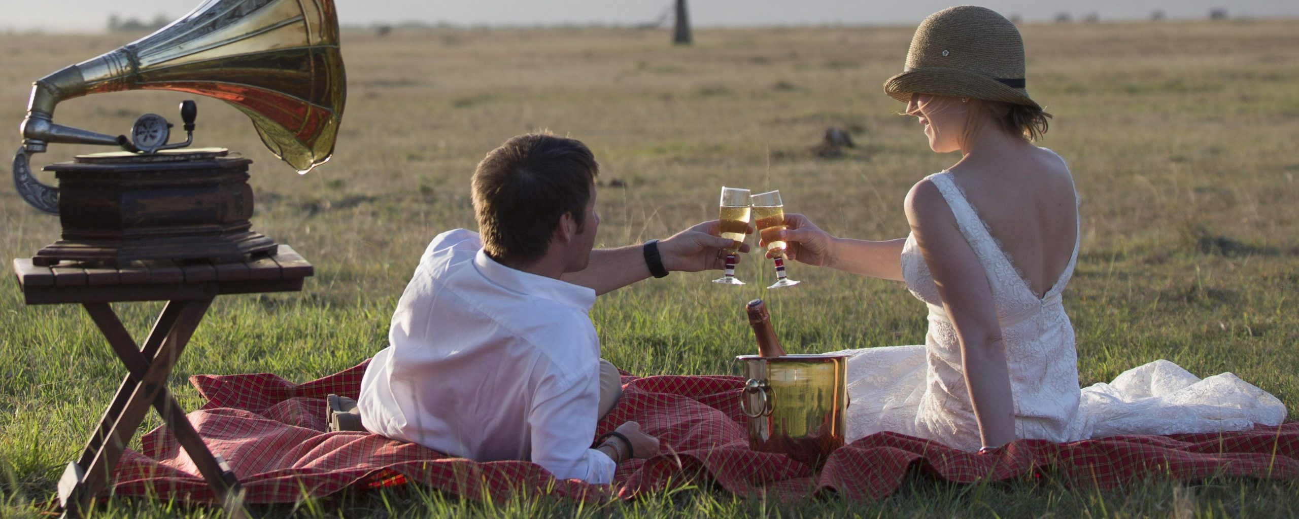 A newlywed couple toast with champagne in the Masai Mara, Kenya
