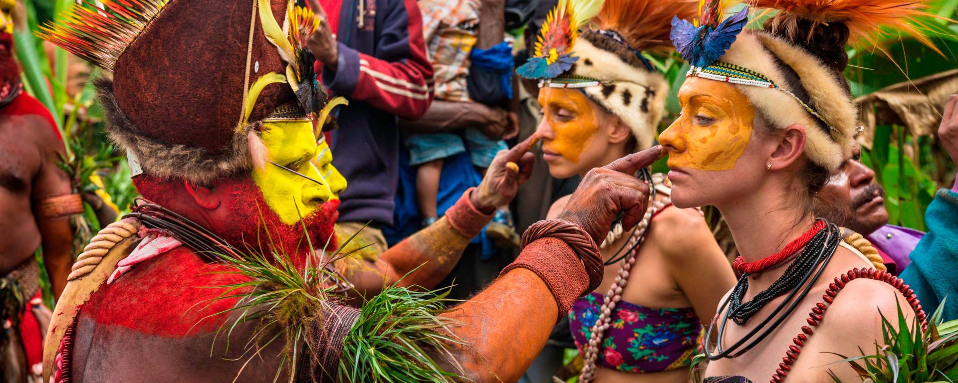 Tribesmen paint the faces of visitors during a traditional sing-sing in Papua New Guinea's Mount Hagen