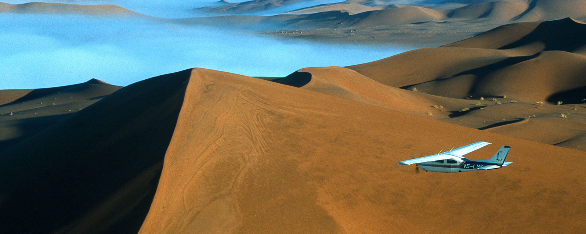 Safari flights over red sand dunes of Sossusvlei with early morning mist, Namib-Naukluft National Park, Namibia.