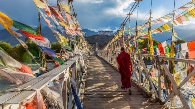 A monk walks across a bridge covered in prayer flags in Leh, in the Ladakh region of India