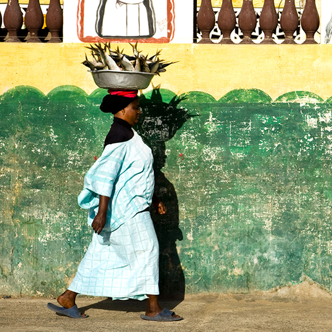 Senegalese woman walking with a large bowl of fresh fish atop her head.