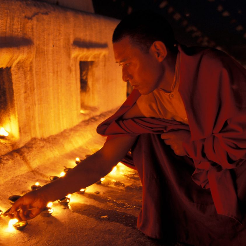 Monk lighting butter lamps at Boudnath, Kathmandu Nepal.