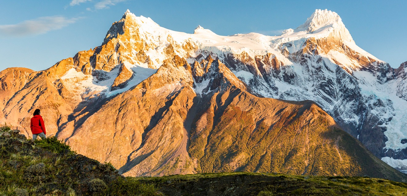 A hiker admires sunrise on Cerro Paine Grande, Torres del Paine, Chile