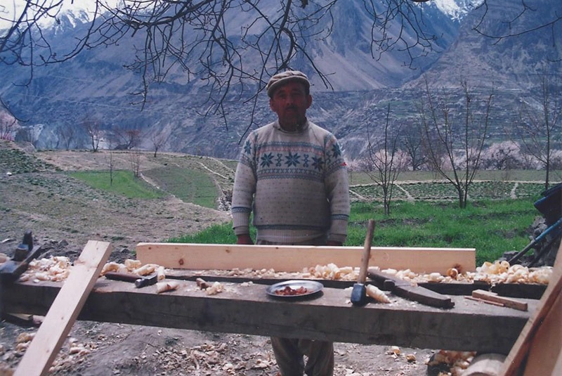 A carpenter works on a door outside of a home in Hunza, Pakistan