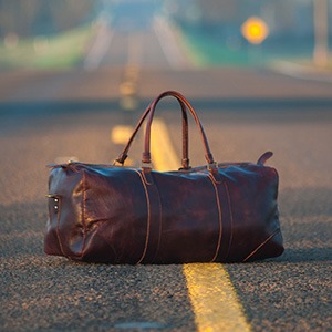 A duffle bag lies in the middle of a road