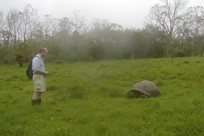 Don George in a field with a giant tortoise in the Galapagos