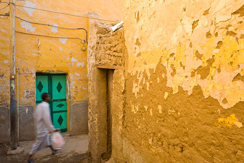 Man walking through yellow buildings in a Nubian Village, Egypt