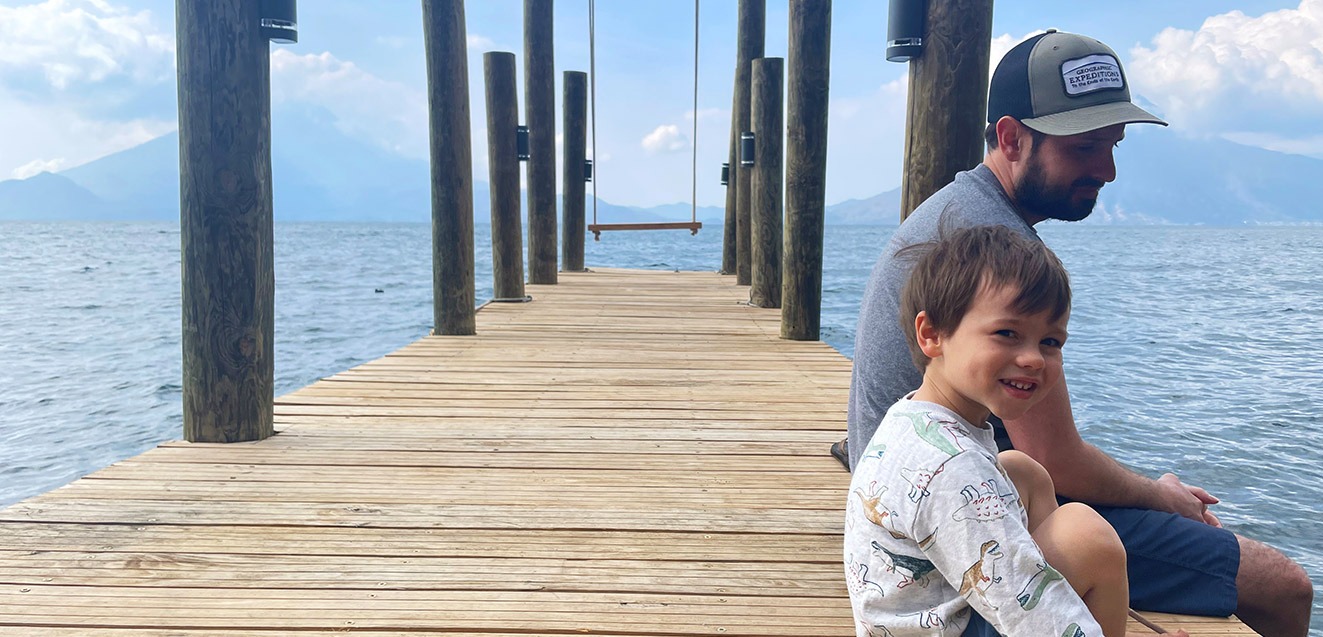 GeoEx's Alex Yalch sitting on a deck at Lake Atitlan with his son