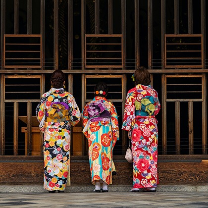 Women in traditional dress in front of wooden gate in Kyoto, Japan