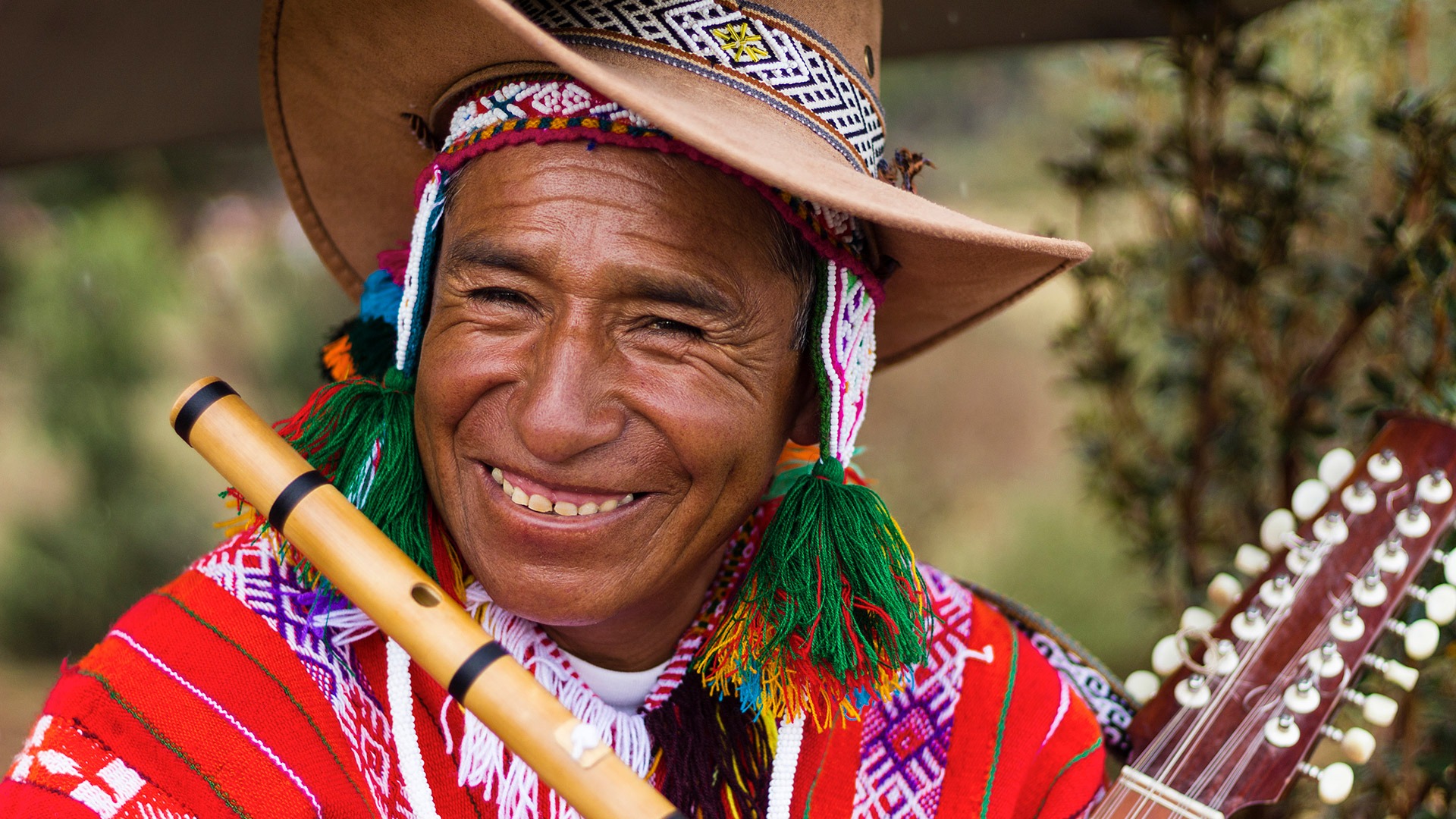 Smiling musician with flute and string instrument near Cusco, Peru