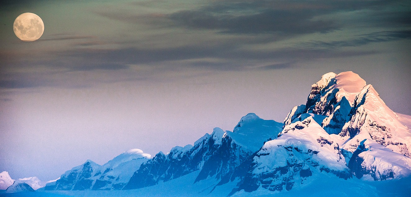 Full moon over snowy Antarctica peaks