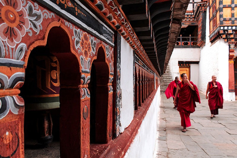 Buddhist monks walk along prayer wheels in Bhutan