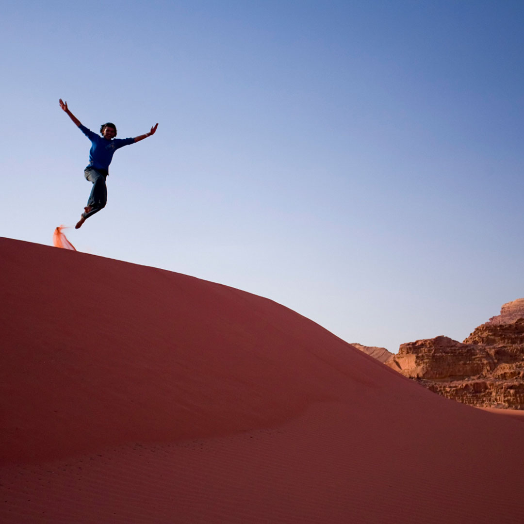 Person running down a sand dune in Jordan